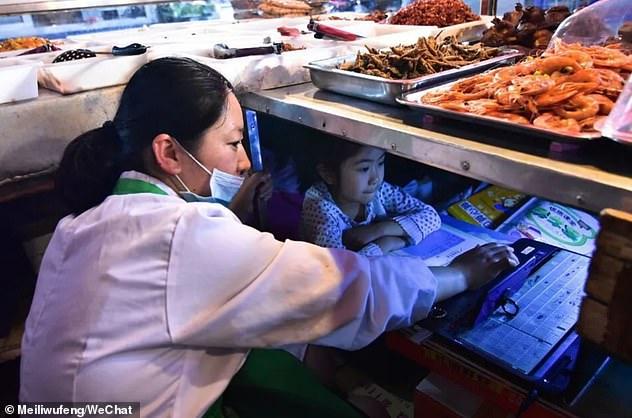 Mai avem curajul să ne plângem? Fetița asta își face temele sub taraba la care mama ei vinde pește: „I-am încropit un birou” - FOTO