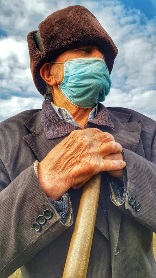 Imagini virale cu un bătrân, la câmp, purtând mască de față: "Avea una veche, refolosită. A spus că o poartă că așa au zis conducătorii țării că trebuie"