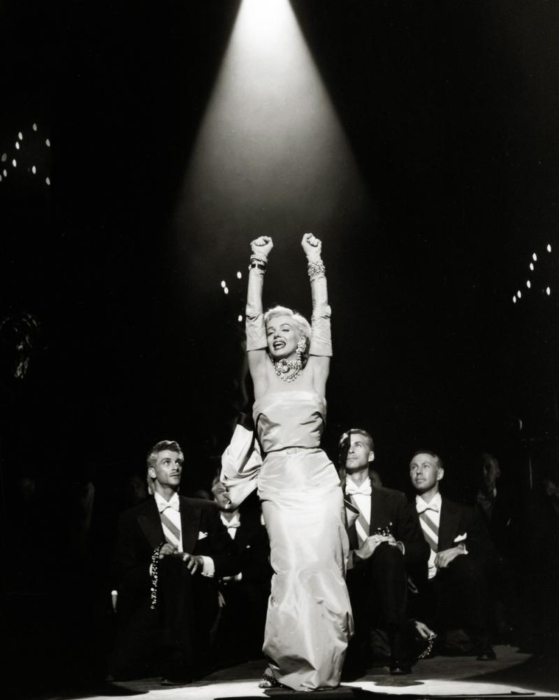 Marilyn Monroe într-o rochie lungă, cu brațele în aer