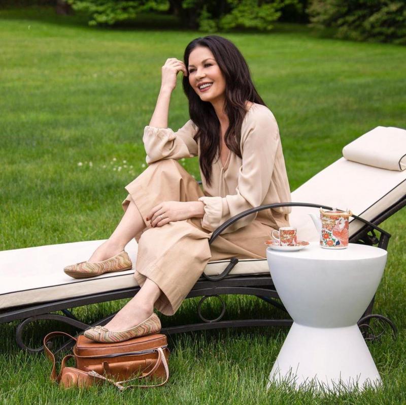 catherine zeta-jones intr-o rochie bej, pe un sezlong in curte