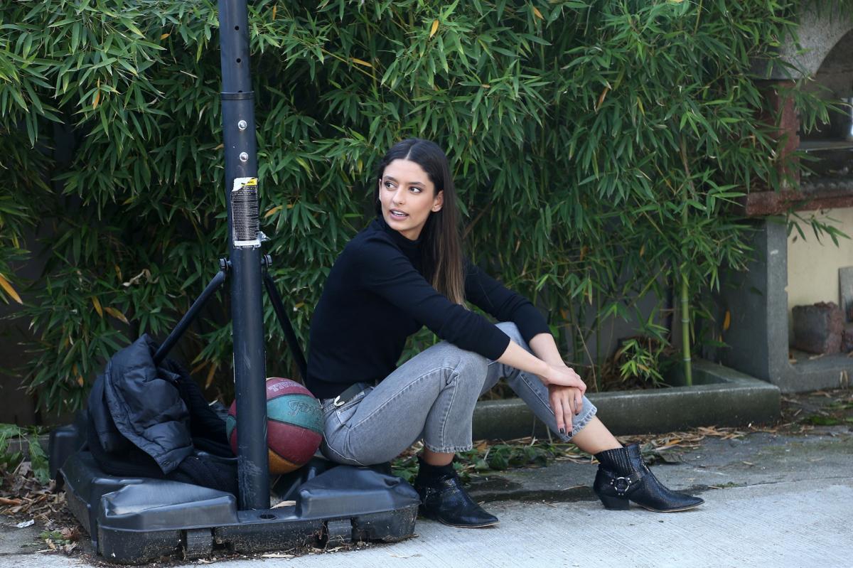 Oana Moșneagu poartă o bluză neagră și pantaloni gri
