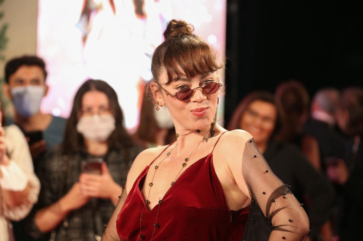 Demet Evgar poartă o salopetă vișinie și ochelari de soare. Actrița are părul prins în coc