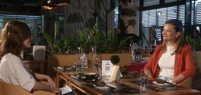 Eli Neicuț poartă o bluză albă și un sacou portocaliu