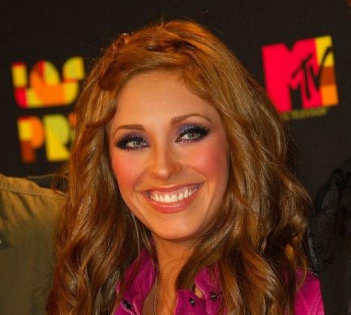 Anahi poartă părul desprins și ondulat și are un machiaj natural