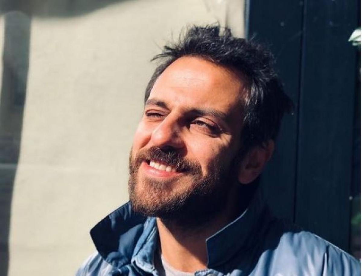 Erkan Kolçak poartă o geacă albastră și are un ochi închis