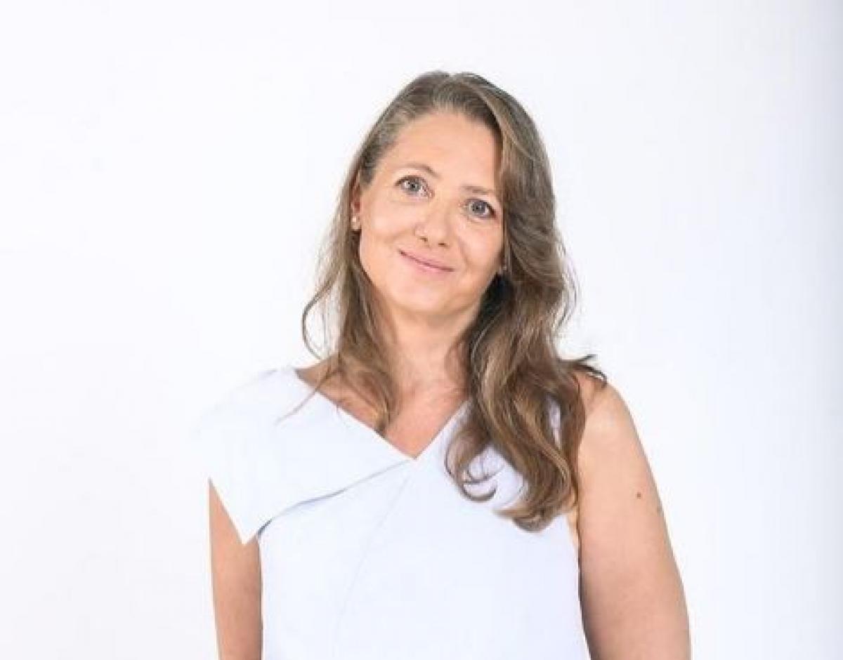 Ioana Abur poartă o rochie albă și are părul desprins