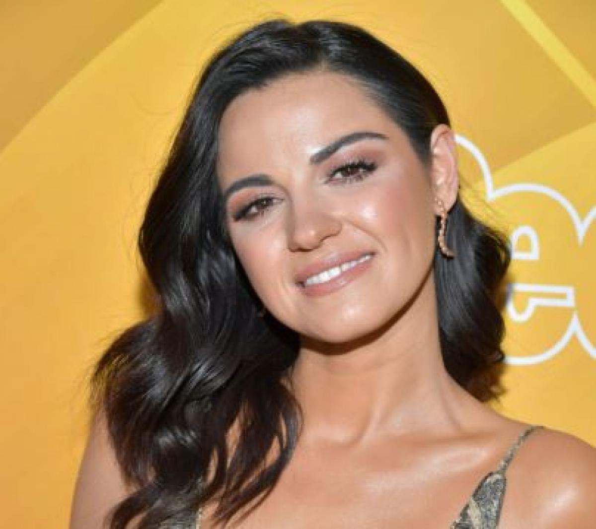 Maite Perroni poartă un machiaj naturaj și are părul desprins și ondulat lejer