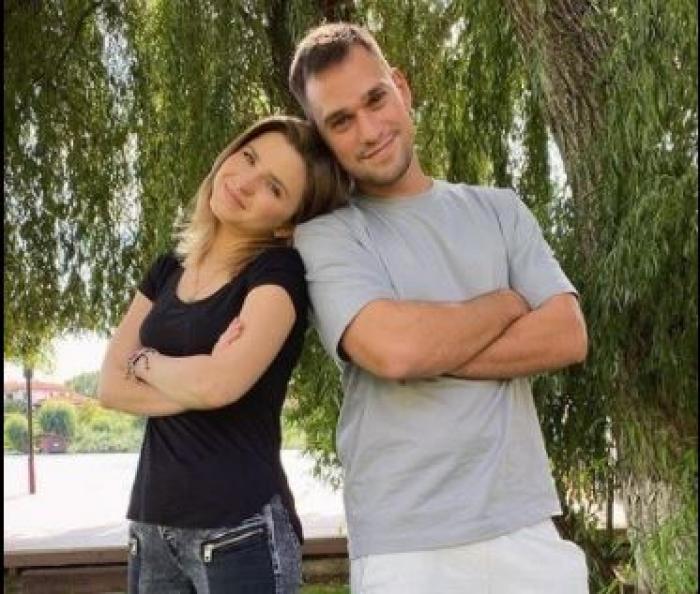 Cristina Ciobănașu poartă un tricou negru și Vlad Gherman poartă un tricou gri. Cei doi stau sprijiniți unul de celălalt