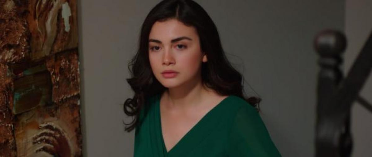 Ozge Yagız poartă o bluză verde și are părul desprins și ondulat