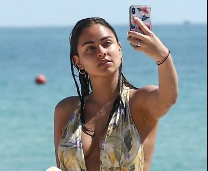 Claudia Martin poartă un costum de baie întreg și se pregătește să-și facă un selfie