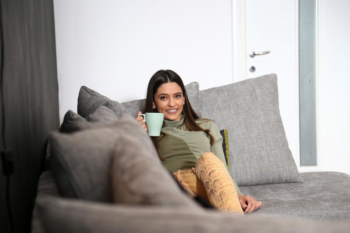 Oana Moșneagu poartă pantaloni deschiși la culoare și are părul desprins