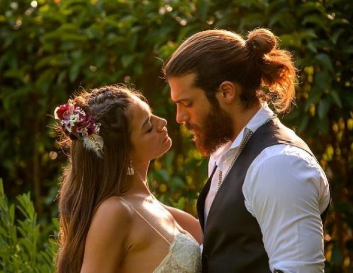 Can Yaman poartă o cămașă deschisă la culoare, iar Demet Ozdemir poartă o rochie fără mâneci și are părul prins lejer