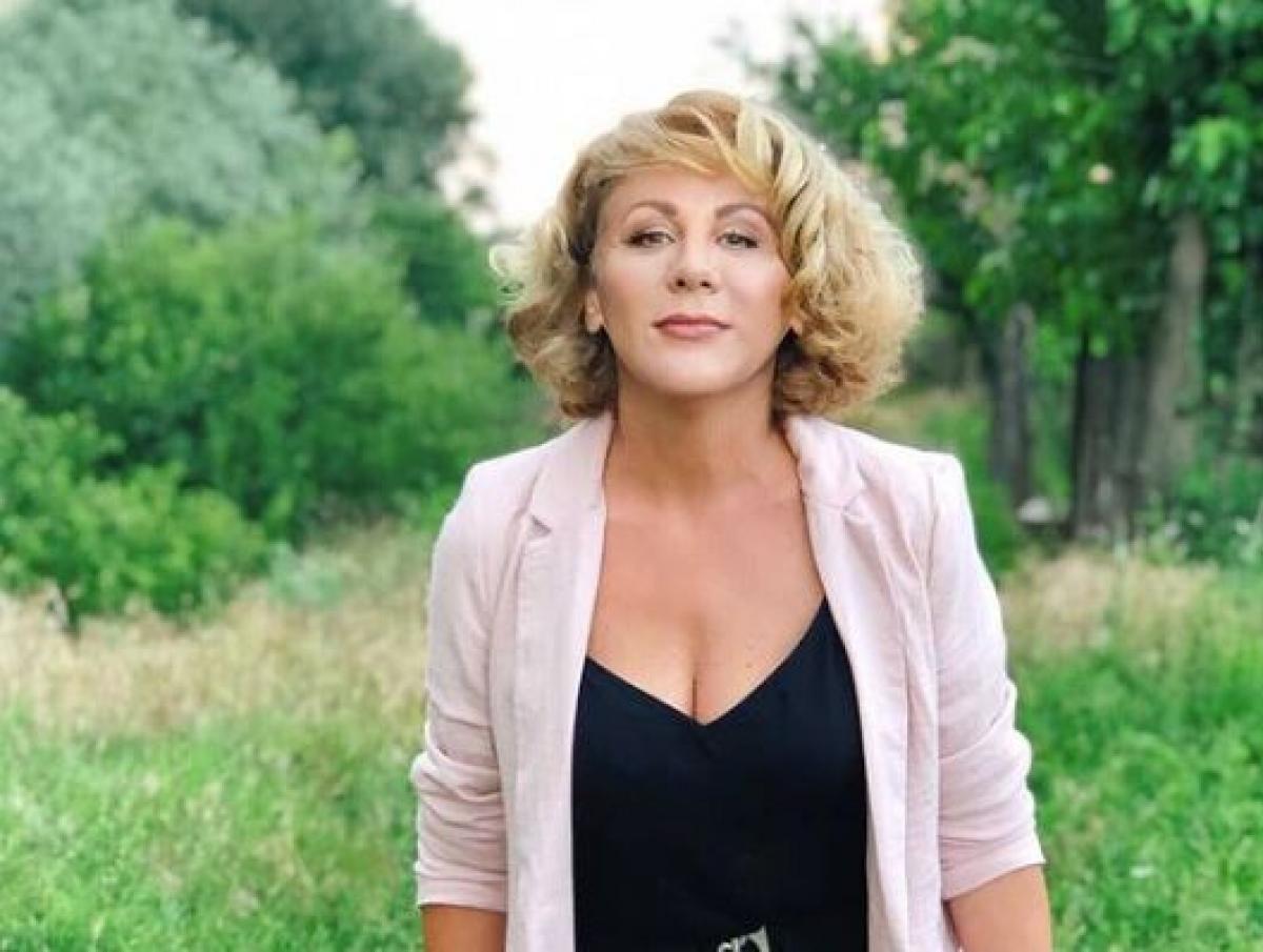 Luminița Erga poartă o bluză neagră cu decolteu adânc și un cardigan roz