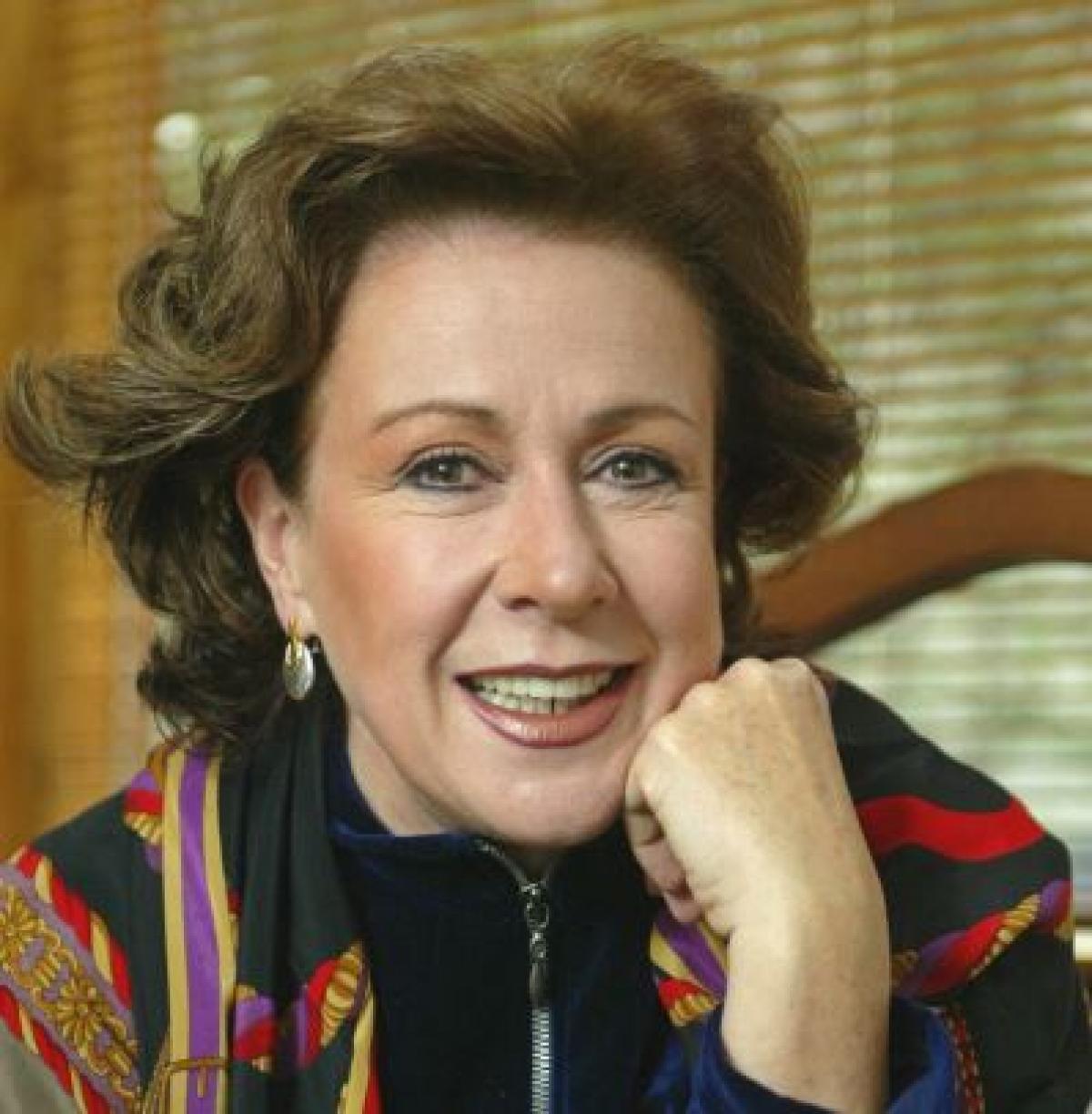 Laura Zapata poartă părul aranjat, are bijuterii și un machiaj lejer, de zi