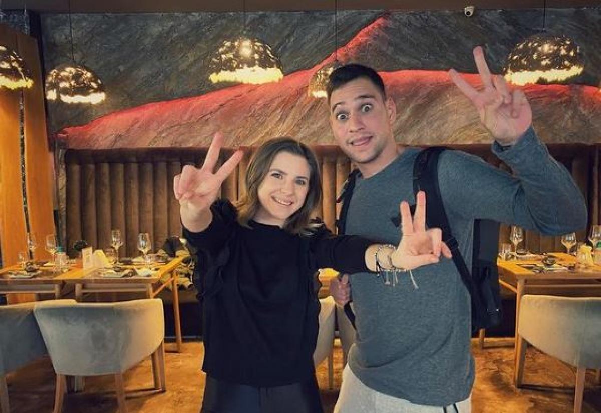 Criss poartă o bluză neagră și are părul desprins, iar Vlad Gherman poartă o bluză albastră cu mâneci lungi