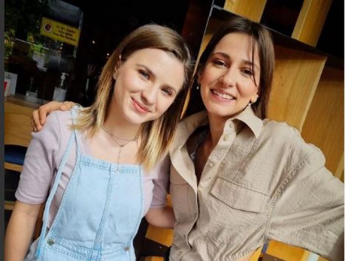 Dana Rogoz este îmbrăcată într-un body maro și pantaloni închiși la culoare și o ține de umăr pe Cristina Ciobănașu