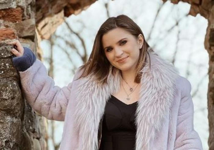 Cristina Ciobănașu poartă o haină de blană de culoare mov și are părul desprins