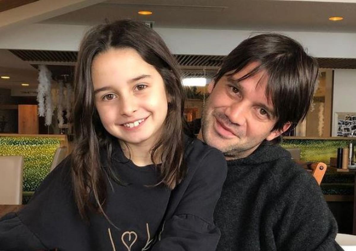 Cristi Chivu își ține fiica în brațe. Amândoi sunt îmbrăcați în negru