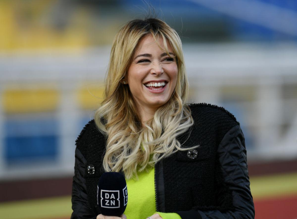 Diletta Leotta poartă o bluză verde și o geacă neagră. Jurnalista are părul desprins și râde