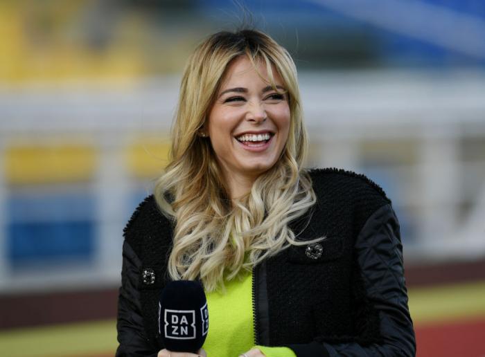 Diletta Leotta poartă o bluză verde și o geacă neagră. Jurnalista are părul desprins și râde