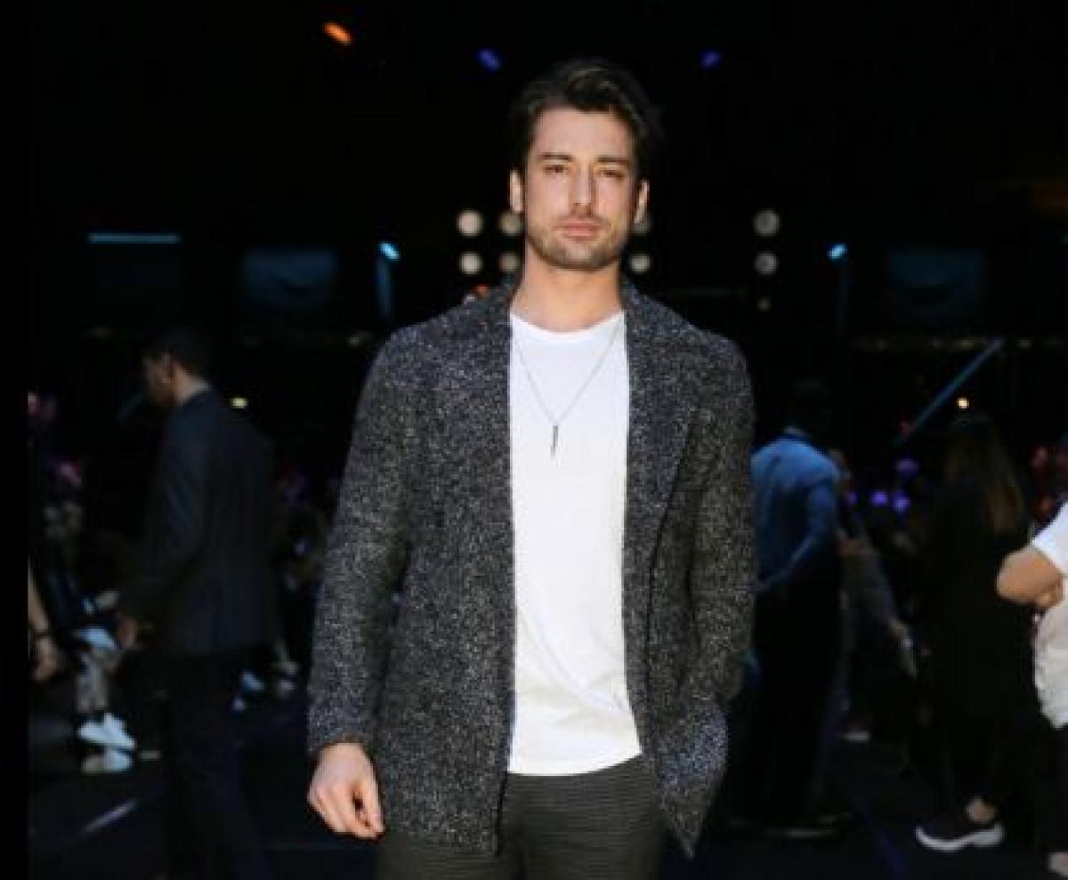 Alp Navruz poartă un tricou alb și un sacou gri