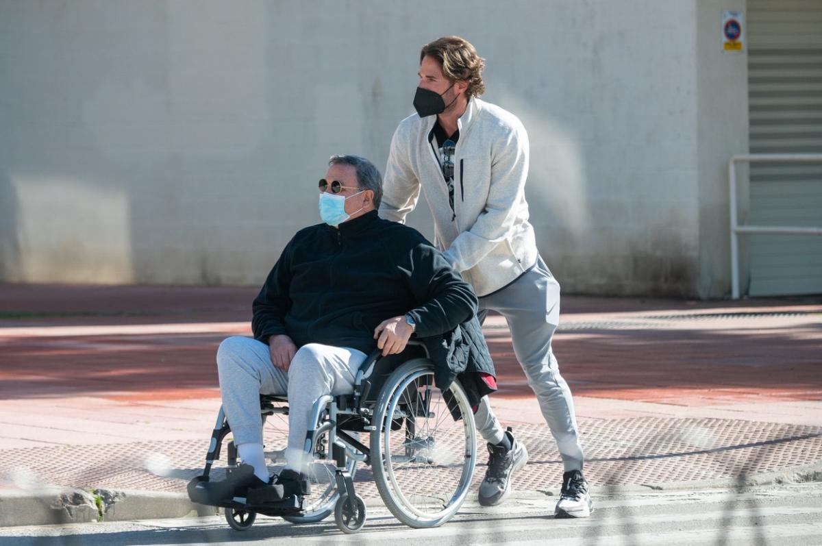 Sebastian Rulli împinge căruciorul în care se află tatăl lui și este îmbrăcat sport. Actorul poartă o mască de protecție