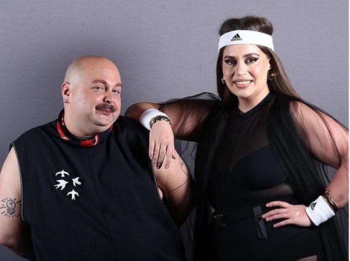 Zarug este îmbrăcat în negru, iar Lorelei Bratu de asemenea. Aceasta poartă o bentiță albă de sport