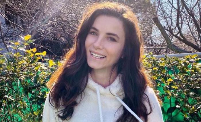 Cansu Tuman poartă un hanorac alb și are părul desprins