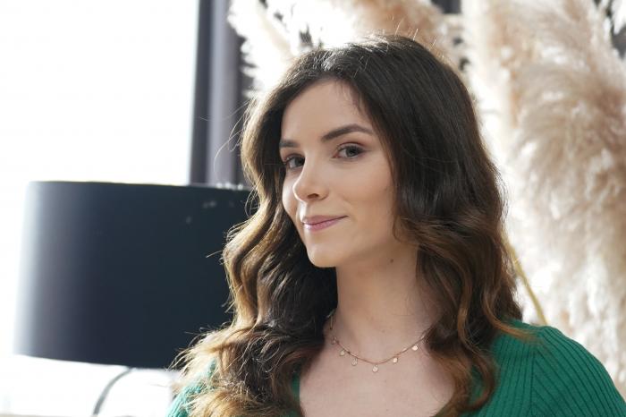 Cansu Tuman poartă o bluză verde și are părul desprins