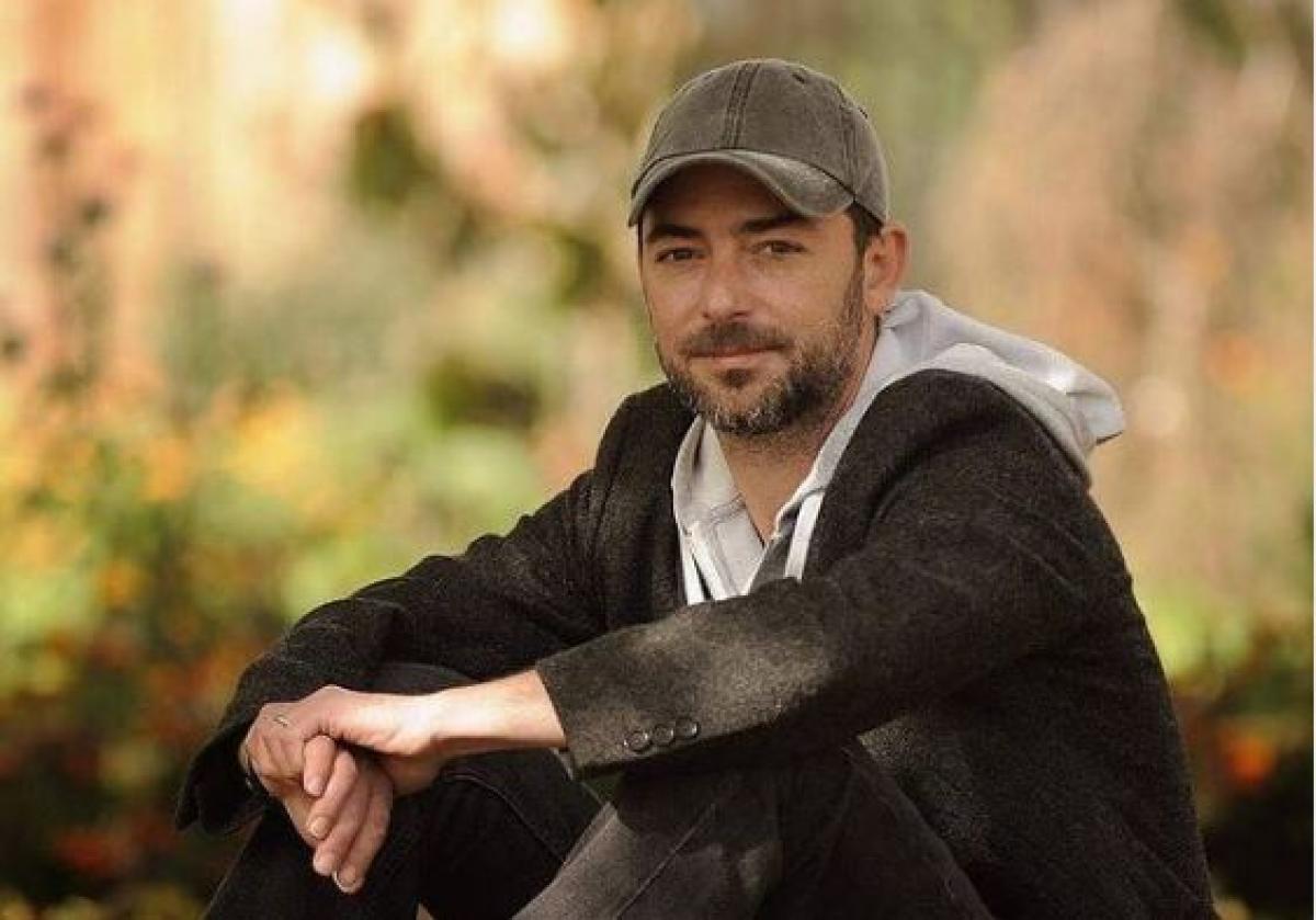 Dan Bordeianu este îmbrăcat în blugi închiși la culoare, hanorac alb și un sacou închis la culoare. Actorul are șapcă