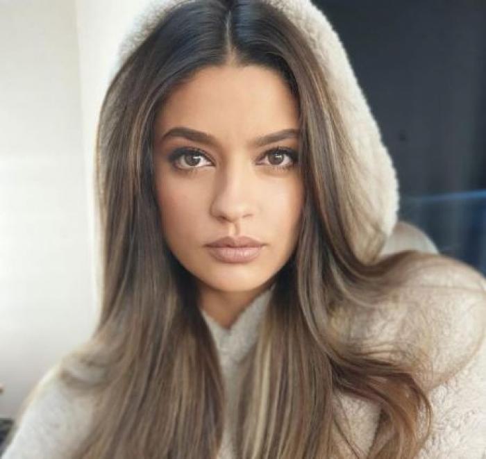 Oana Moșneagu este îmbrăcată cu un hanorac și are gluga trasă pe cap. Actrița poartă părul desprins