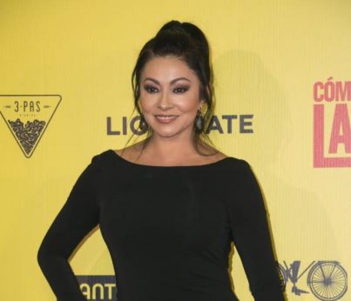 Paty Diaz este îmbrăcată într-o rochie neagră, lungă cu mâneci lungi și are părul prins