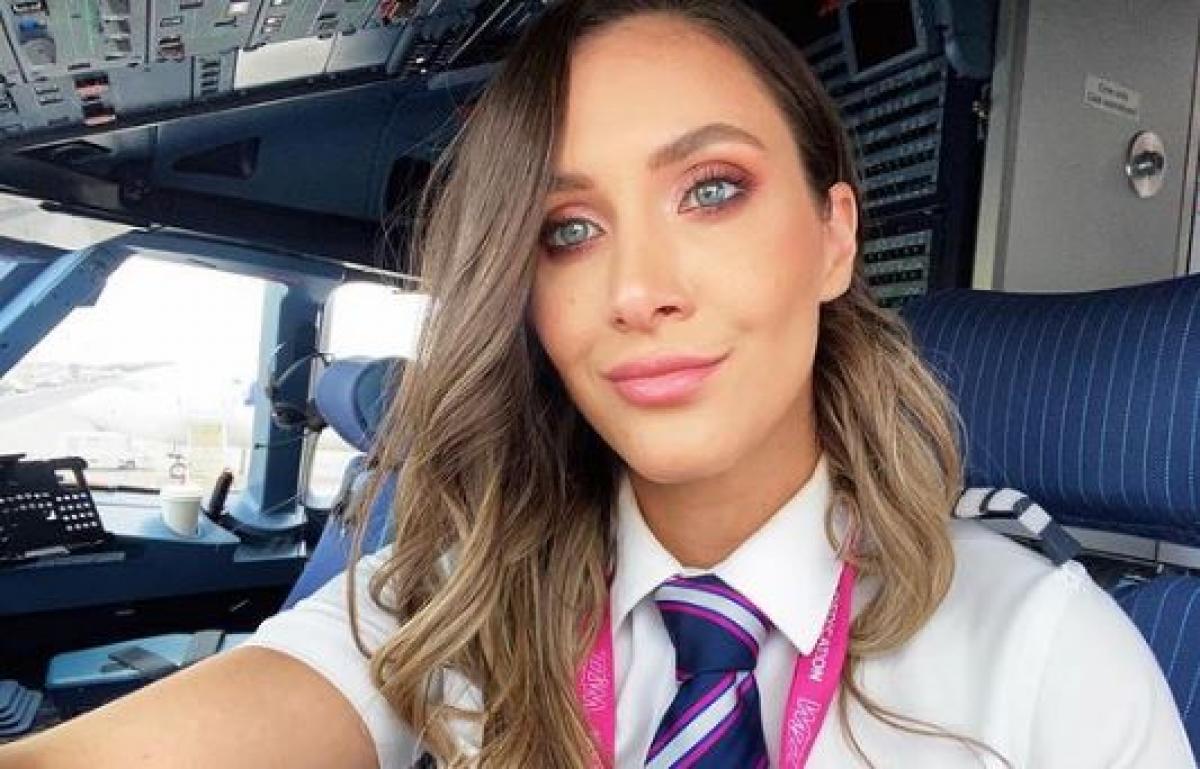 Andreea Lițescu poartă părul desprins și ondulat și este îmbrăcată cu uniforma de pilot