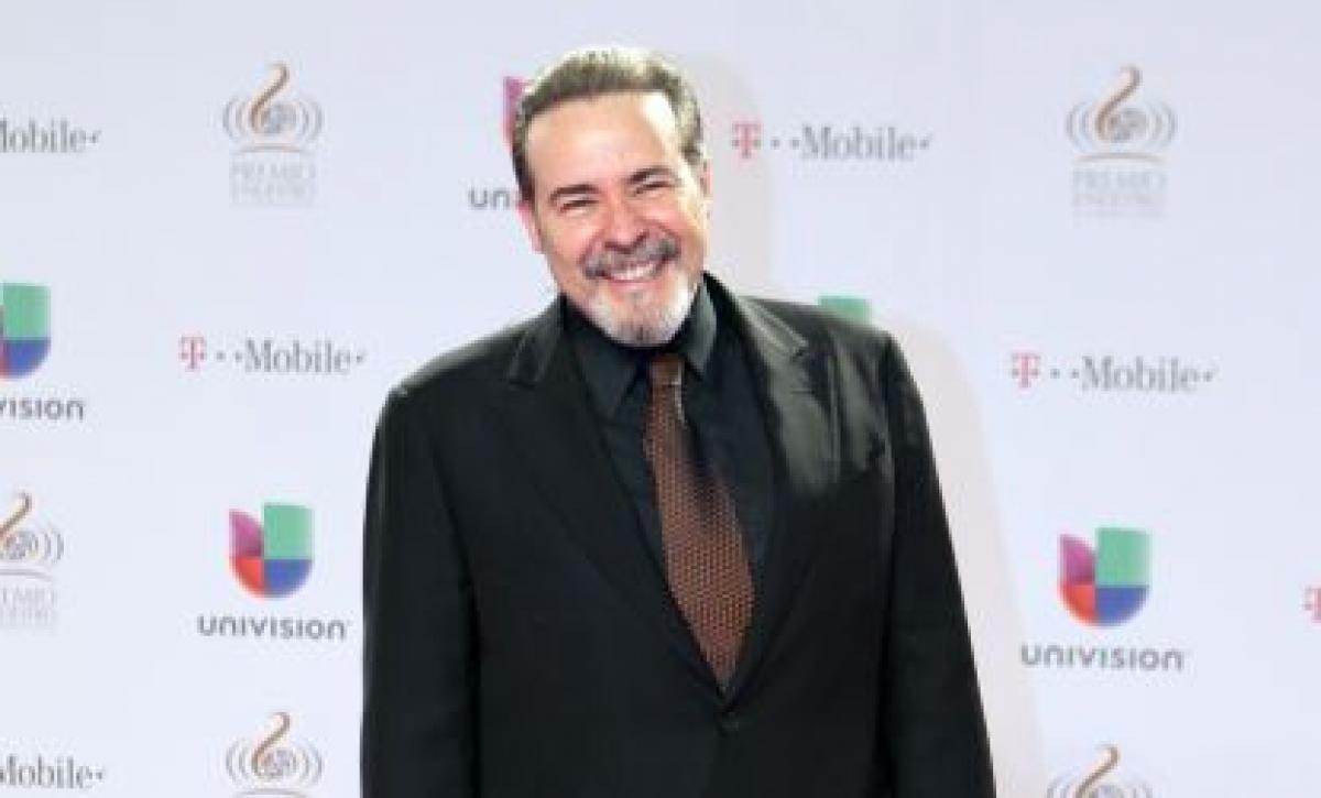 Cesar Evora este îmbrăcat într-un costum închis la culoare și are barba albă