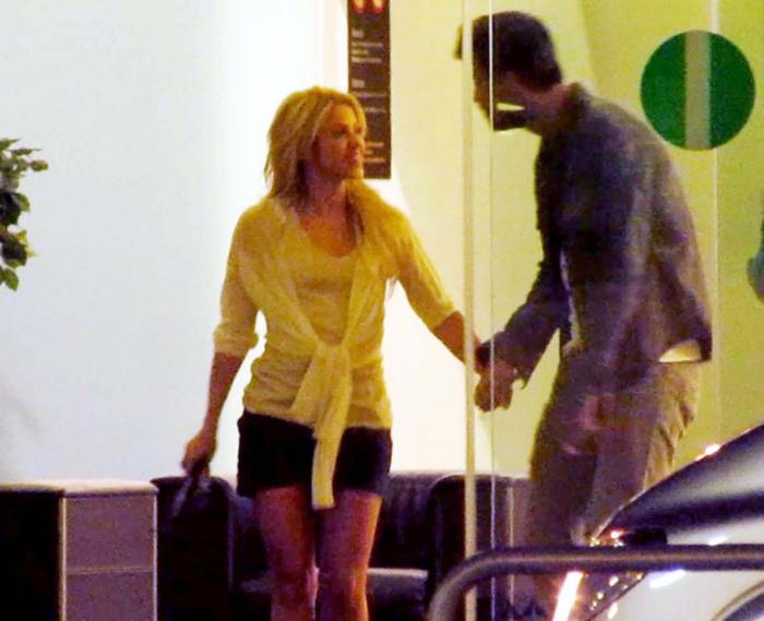 Shakira poartă o fustă scurtă și o bluză albă și este ținută de mână de Pique