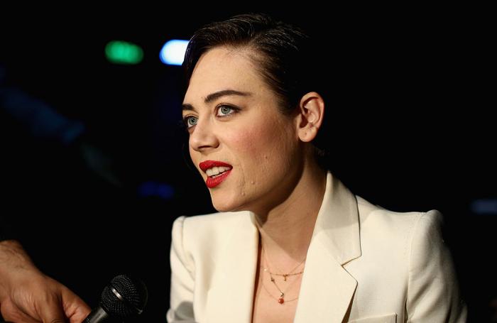 Demet Evgar poartă un sacou alb și are părul prins. Actrița din Flăcările Destinului are ruj roșu