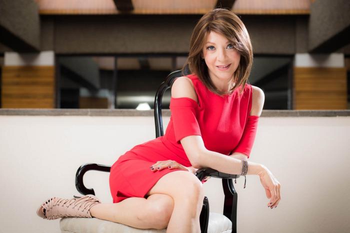 Edith Gonzalez poartă o rochie roșie scurtă și are perucă