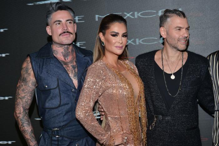 Ninel Conde poartă o rochie de seară și are un machiaj în ton cu evenimentul. Se află între doi bărbați