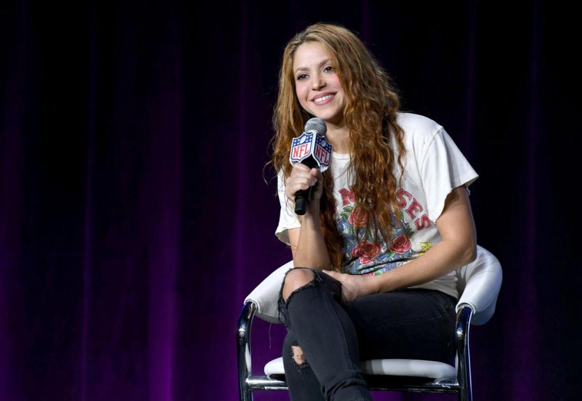 Shakira poartă blugi negri rupți în genunchi și are un tricou cu imprimeu