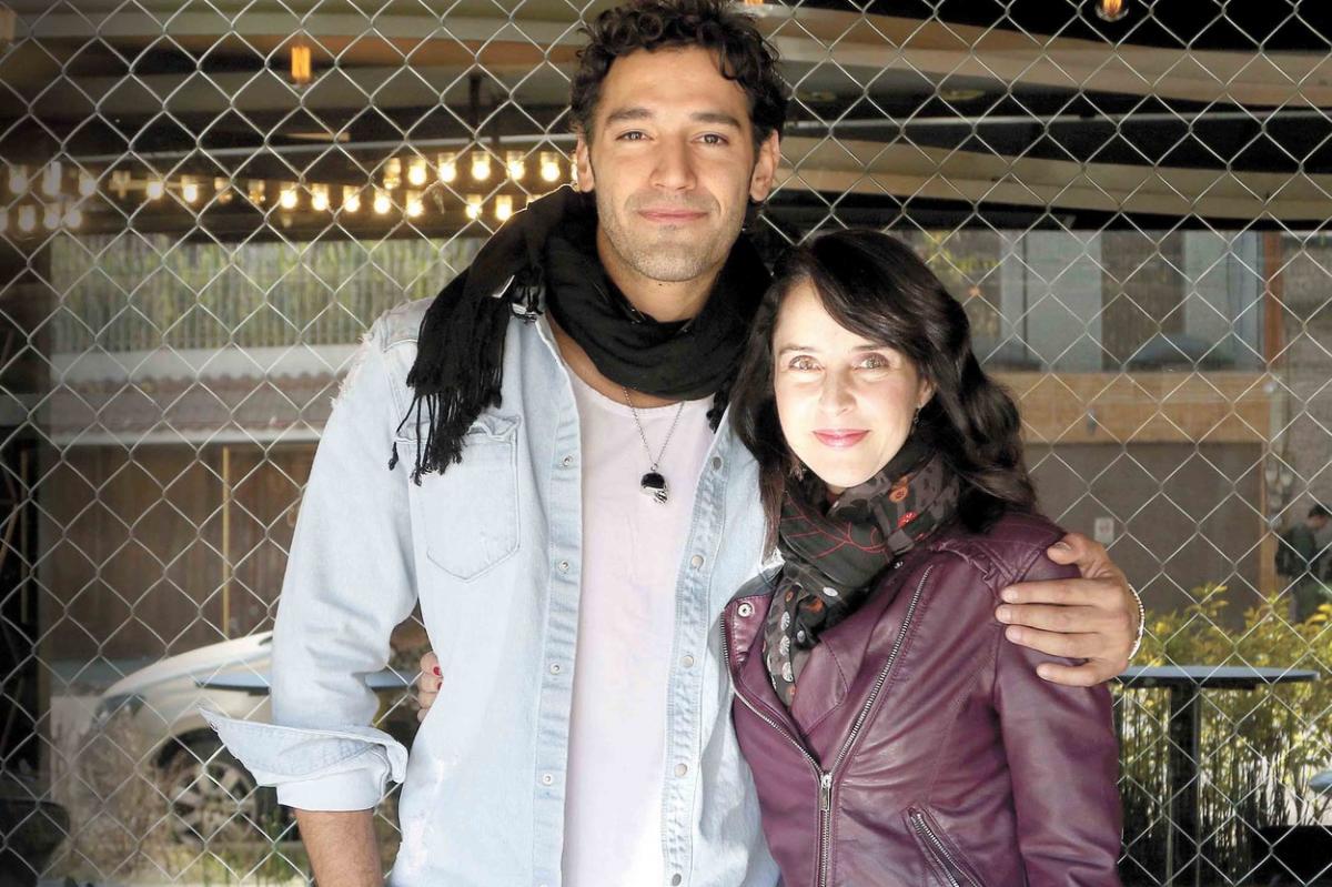 Iran Castillo poartă o geacă mov de piele și are o eșarfă în jurul gâtului