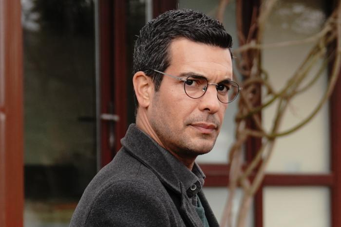 Can Verel poartă ochelari și haine închise la culoare