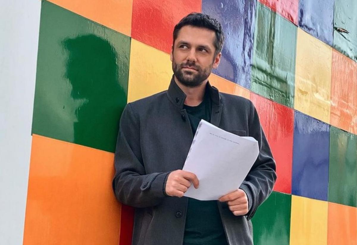 Alecsandru Dunaev poartă pantaloni închiși la culoare și un palton asortat