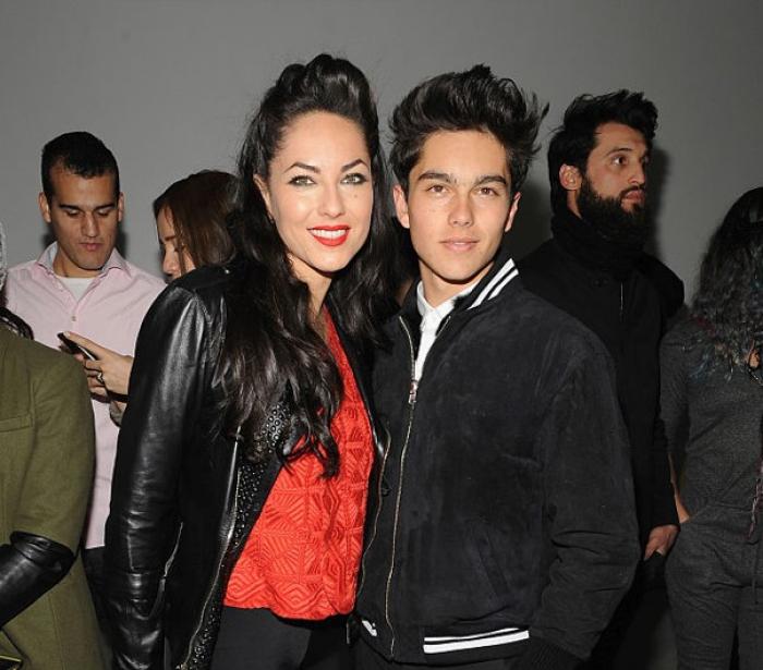 Barbara Mori poartă o bluză roșie și o geacă neagră de blugi și stă alături de fiul ei, Sergio Mayer Mori