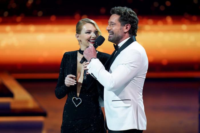 Gabriel Soto poartă un costum alb, iar Irina Baeva este îmbrăcată în negru