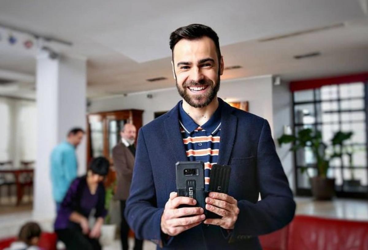 Denis Hanganu poartă un sacou închis la culoare și zâmbește