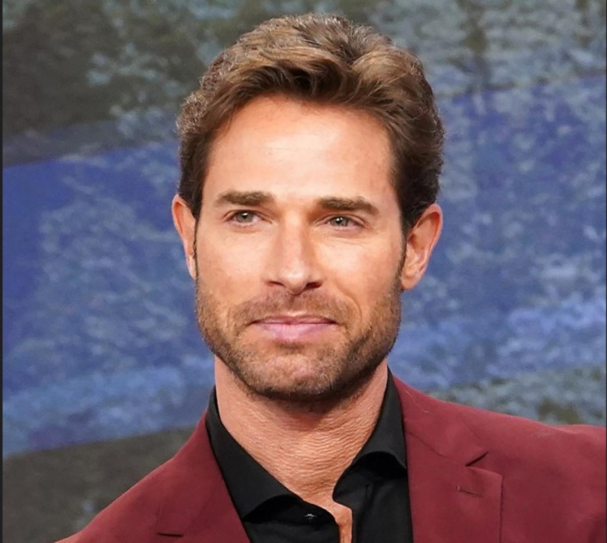 Sebastian Rulli poartă o cămașă neagră și un sacou vișiniu. Actorul are părul scurt și barbă