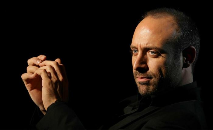 Actrorul Halit Ergenç fotografiat din profil, pe fundal negru, în 2011