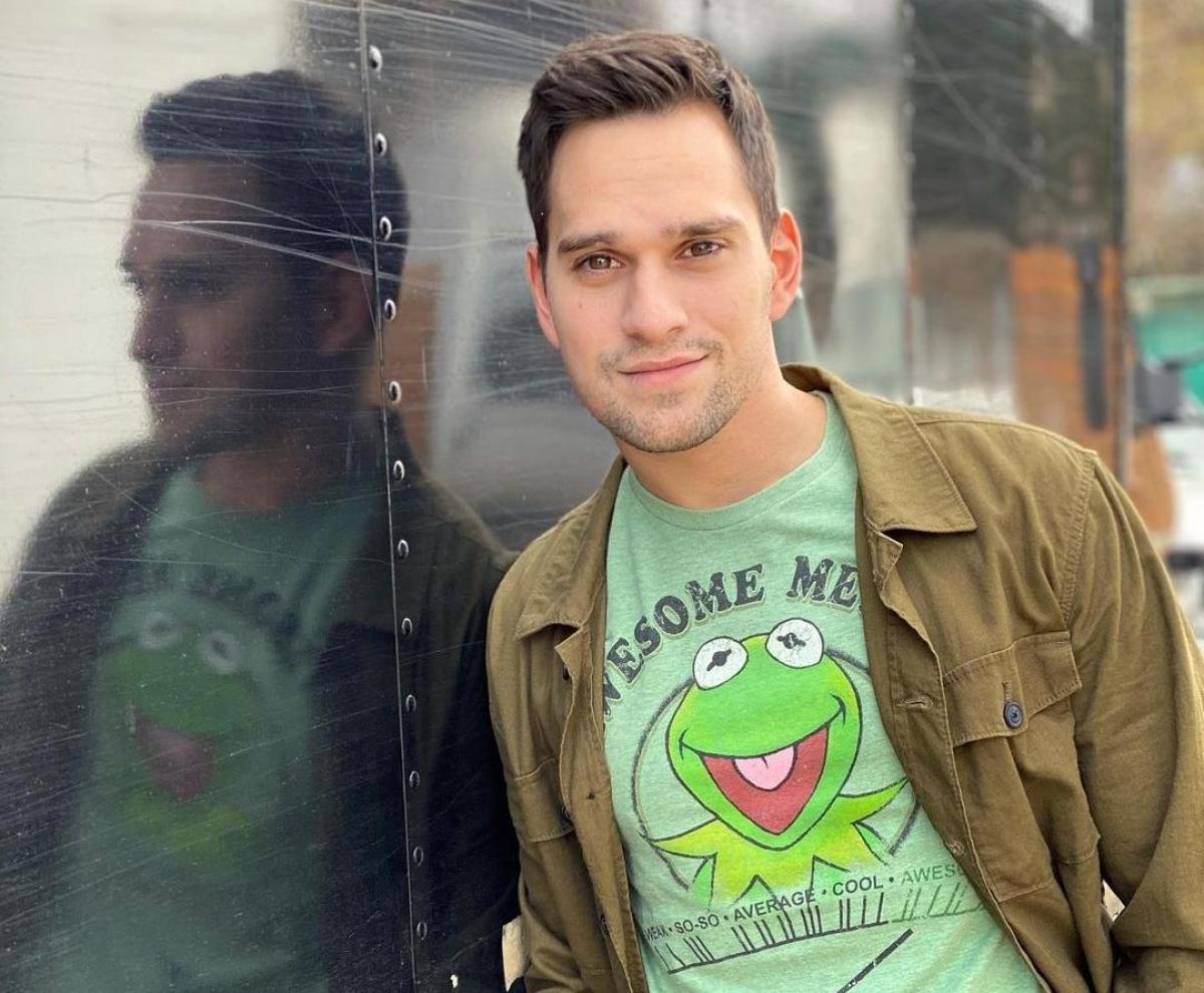 Vlad Gherman îmbrăcat cu un tricou verde și geacă maro, i se vede reflexia într-o tablă de metal
