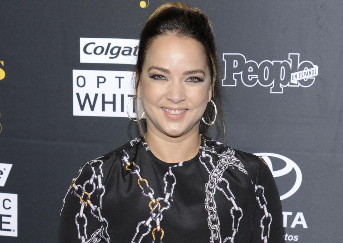 Actrița Adamari lopez, cu o bluză neagră cu imprimeu și părul strâns în coc