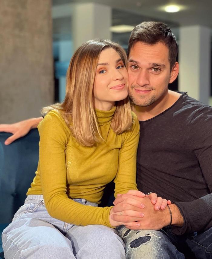 Criss și Vlad, împreună pe o canapea, ținându-se de mână